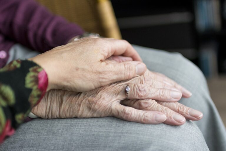 Zartes Handauflegen einer jüngeren Frau auf die Hände einer alten Frau